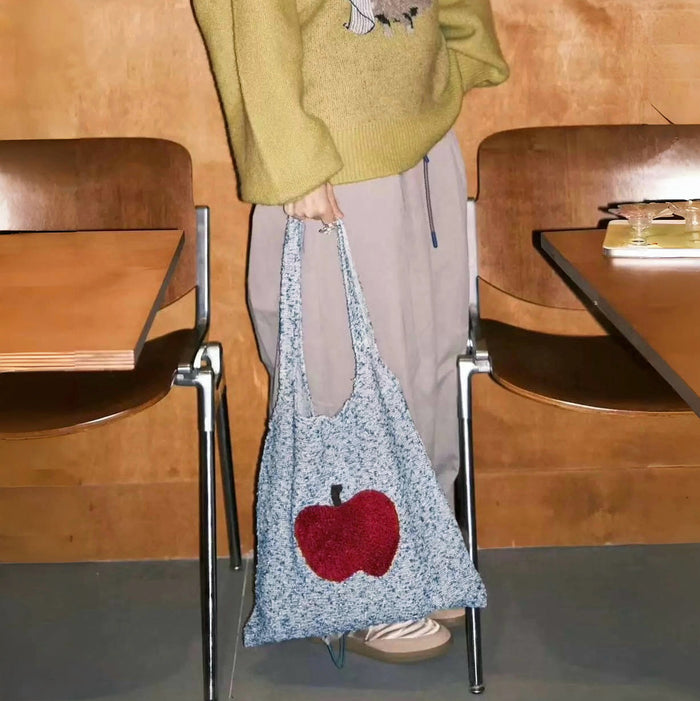 Model carrying an Apple Whimsy Knit Bag handheld , great for daily carry and travel.