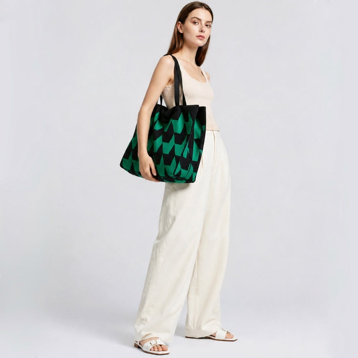 Model carrying oversized arrow print tote bag with green and black geometric pattern, trendy urban streetwear styling.