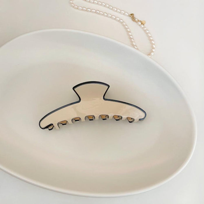 Folded view of Cream Black Border Hair Claw in moon shape, ideal for quick updos and ponytails.