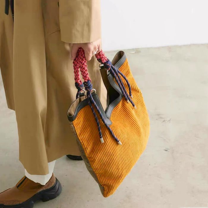 Lifestyle shot of versatile tote bag showing the contrast between mustard corduroy front and braided rope handle details.