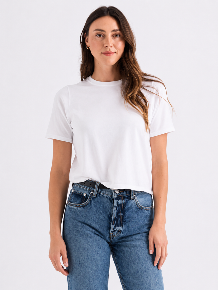 Woman wearing a white t-shirt and blue jeans on a plain background