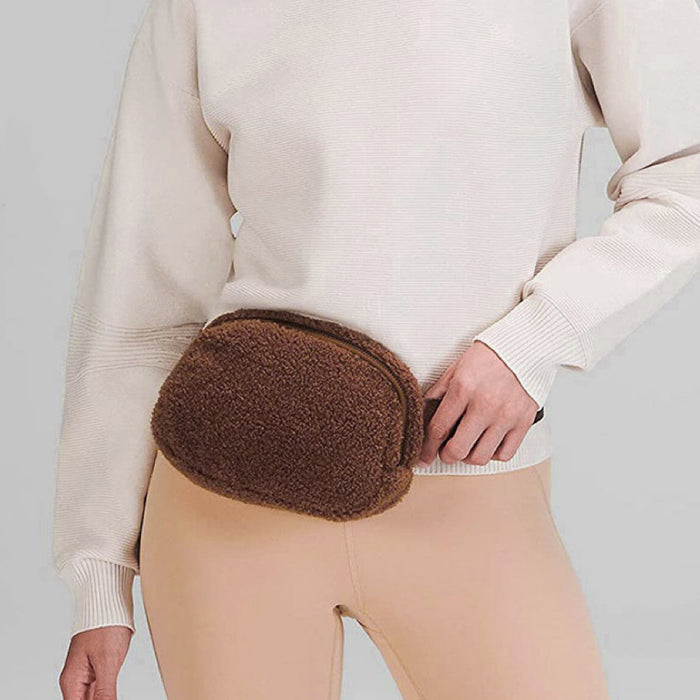 Brown plush belt bag worn over a beige sweater; minimalist and functional sherpa accessory.