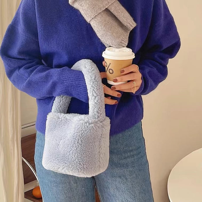 Model carrying a Sherpa Bucket Handbag in blue, ideal for errands and gifting.