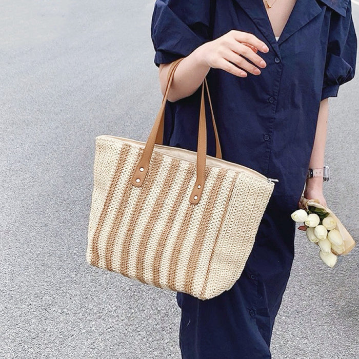 Model carrying a Vertical Striped Straw Tote Bag handheld, great for daily carry and travel.