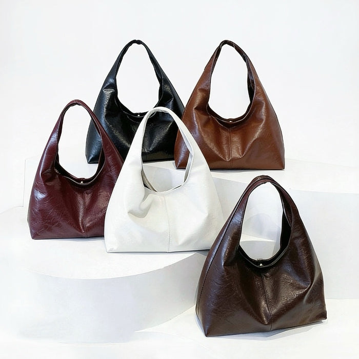 Five waxed leather hobo bags in different colors on a white background