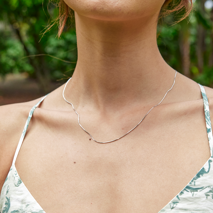 1.0mm Snake Chain in Sterling Silver on a womanʻs neckline outdoors