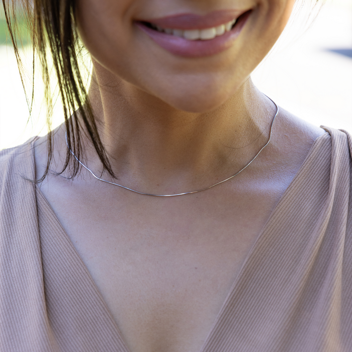 Close up of 1.0mm Snake Chain in Sterling Silver on a womanʻs neckline outdoors