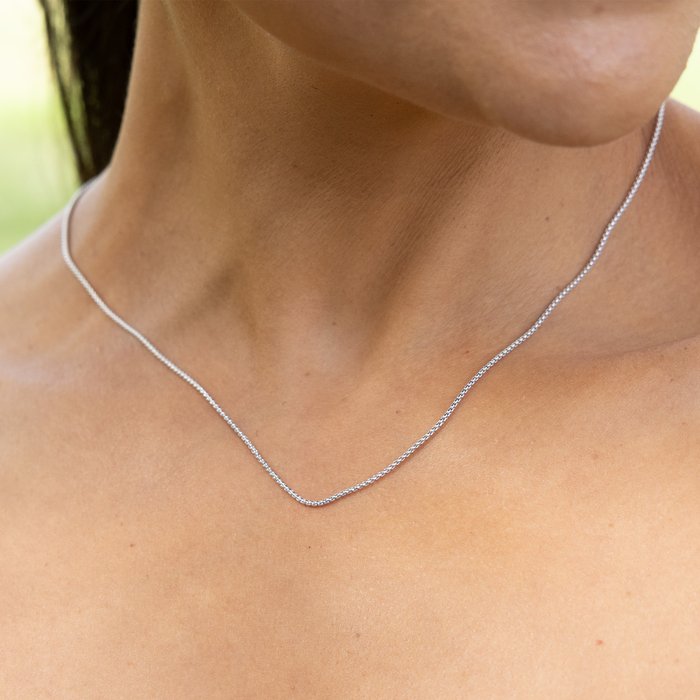 Close up of 1.2mm Round Box Chain in Sterling Silver on a personʻs neck