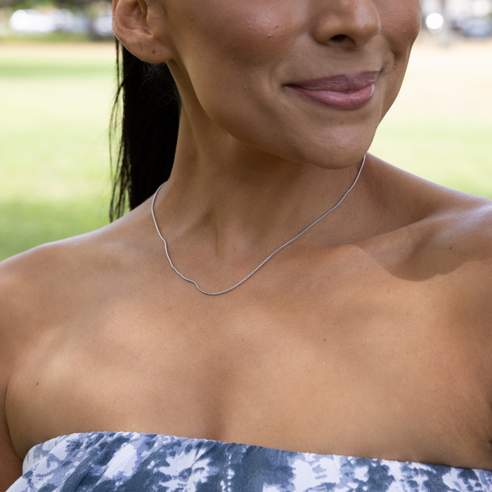 Close up of a woman in a park wearing 1.2mm Round Box Chain in Sterling Silver