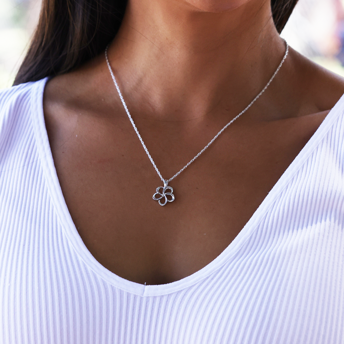Woman in a white top wearing a Plumeria Pendant Necklace in Sterling Silver