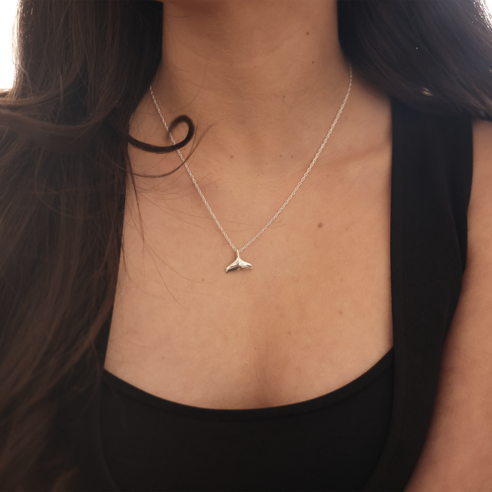 Close up of a Whale Tail Pendant Necklace in Sterling Silver on a woman's chest
