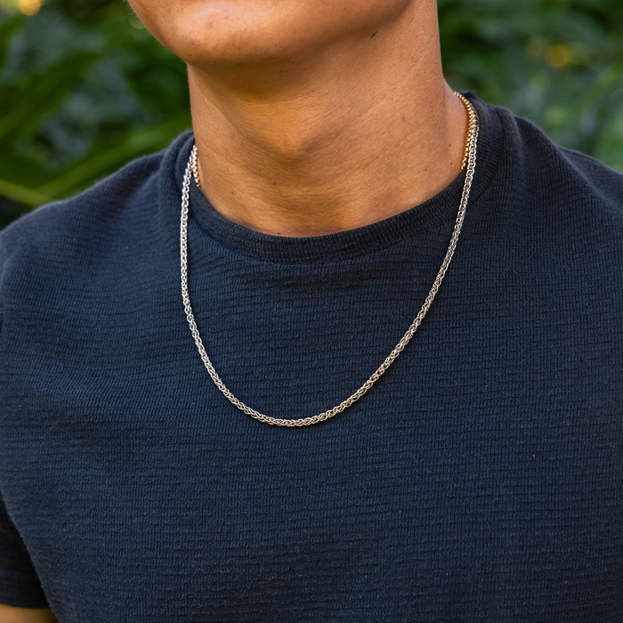 Person in a tropical garden wearing a 2.5mm Espiga Chain in Sterling Silver