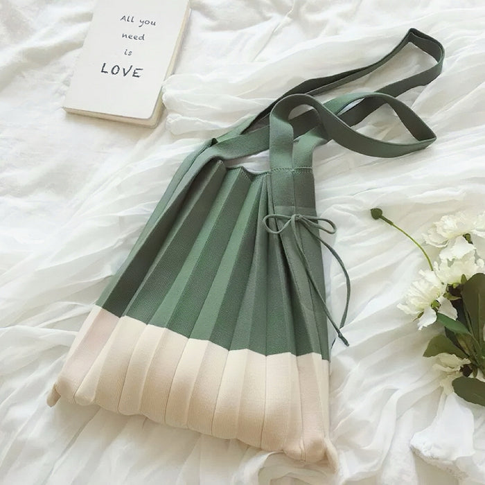 Folded view of Green and cream accordion foldable knitted  bag with shoulder straps.