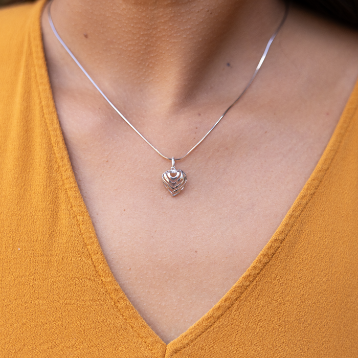 Close up of an Aloha Heart Charm/Pendant in Sterling Silver on a person's chest