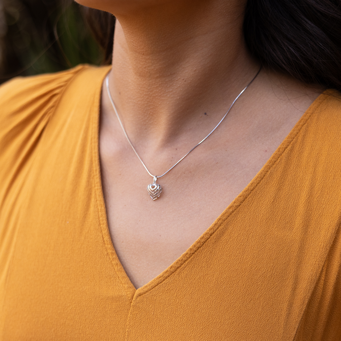 Close up of an Aloha Heart Charm/Pendant in Sterling Silver on a person's chest