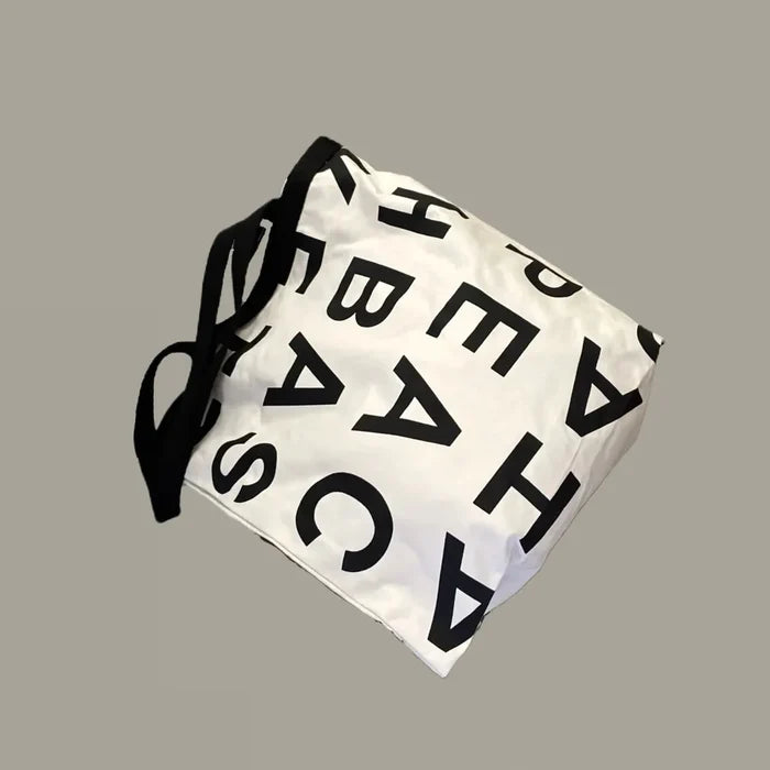 Flat lay of white Alphabet Canvas Tote Bag With Double Strap, great for everyday carry and travel.