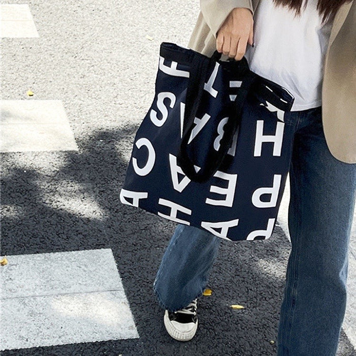 Model carring a black Alphabet Canvas Tote Bag With Double Strap, easy for commuting and weekends.