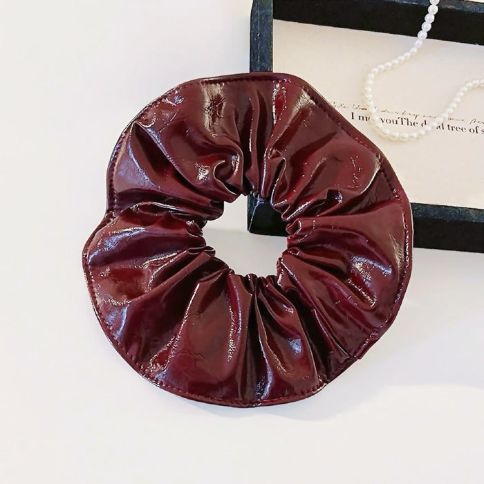 Front view of Ancora red shiny PU leather scrunchie with a ruffled, gathered design.
