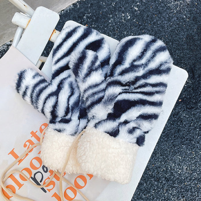 Zebra print fluffy gloves with soft plush texture, flat lay; bold warm accessory for cold days.