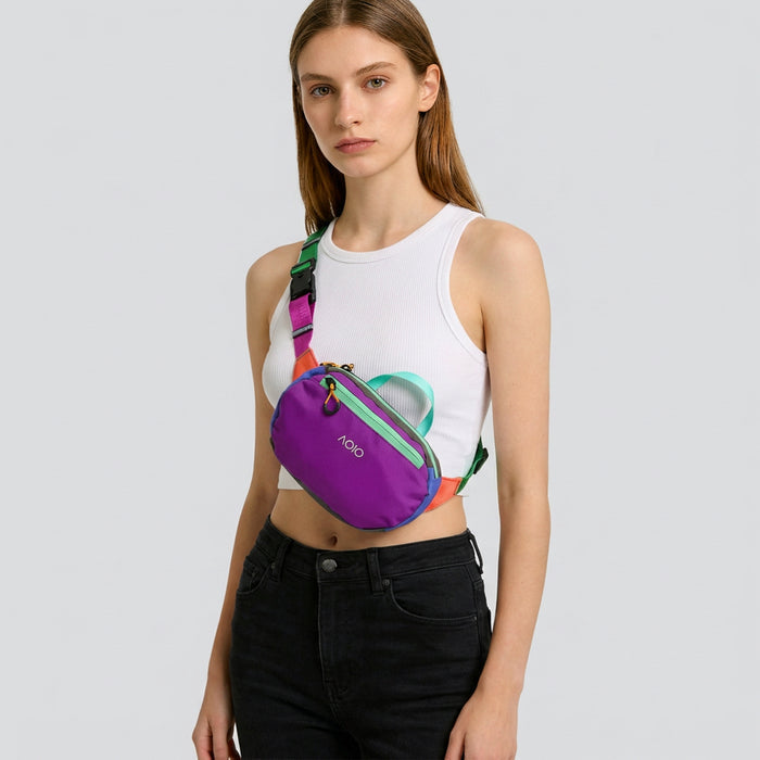 A model wearing a vibrant purple AOIO flex belt bag across the chest.