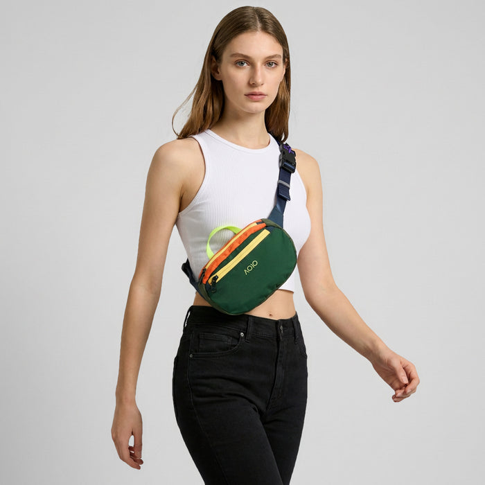 A model wearing the forest green AOIO belt bag as a front crossbody.