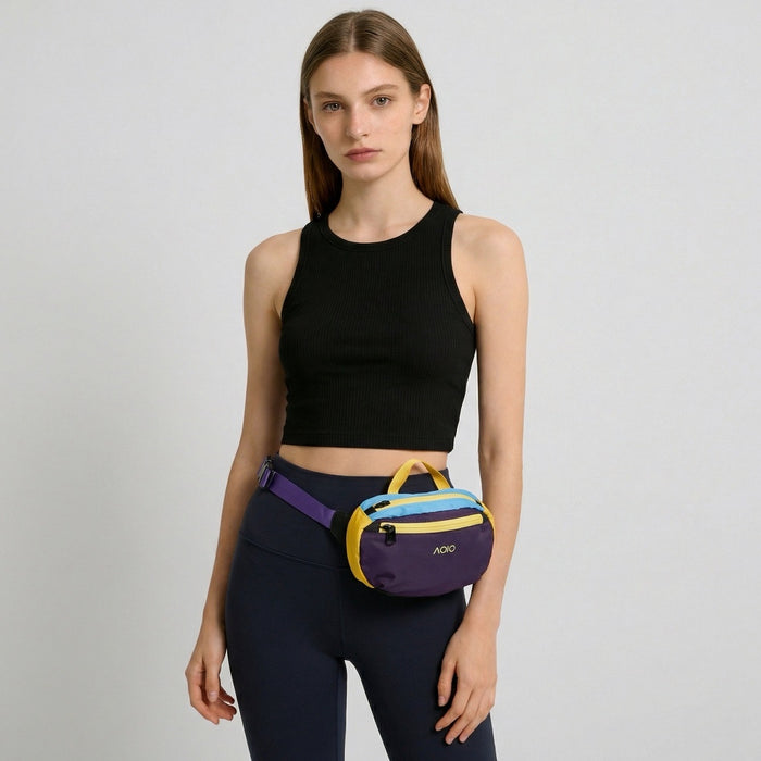 A model wearing the deep purple AOIO belt bag around the waist over dark leggings.