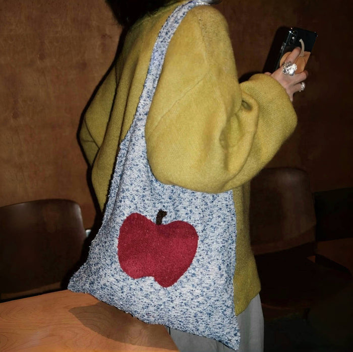 Model carrying a polyester Apple Whimsy Knit Bag on her shoulder, great for daily carry and travel.