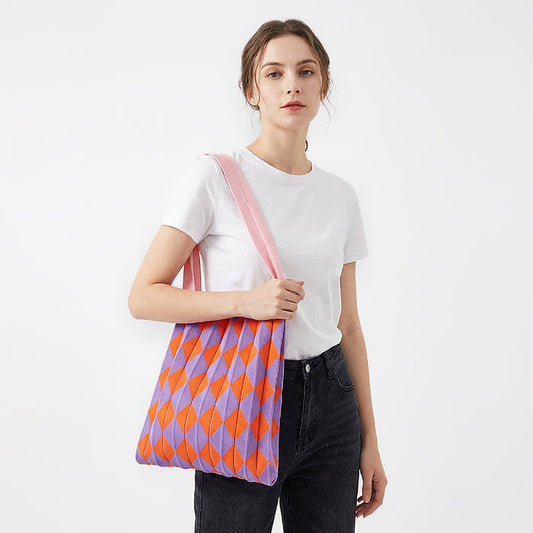 Model styling a purple and orange argyle pleated knit bag for a vibrant look.