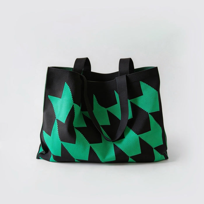 Front view of large knitted tote bag with green arrow print pattern and black strap.