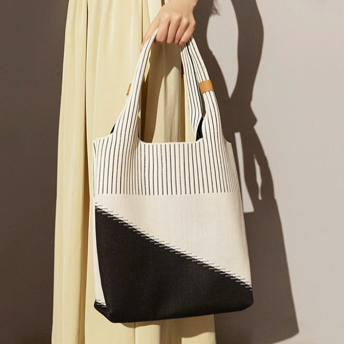Model carrying white and black knitted artistic tote bag showcasing artisanal style for creative professional commutes.