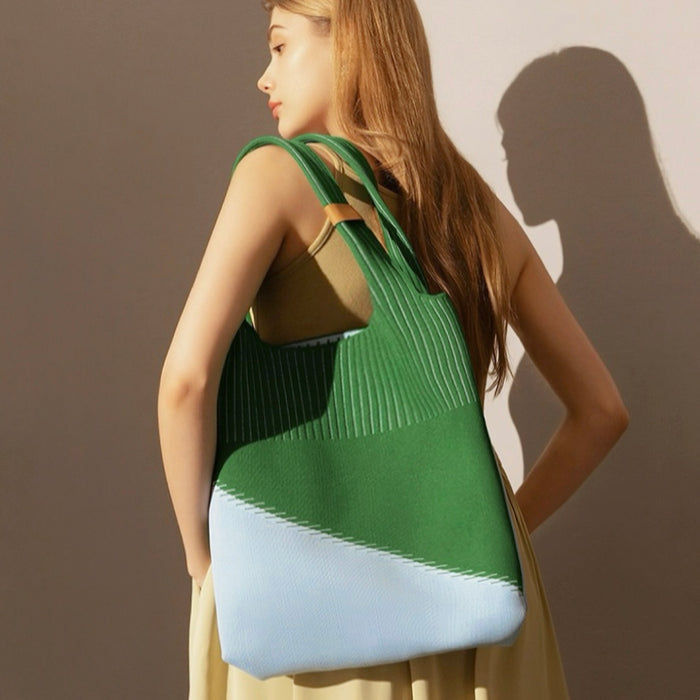 Side view of color-block green and light blue knitted bag highlighting flexible structure and  artistic style.