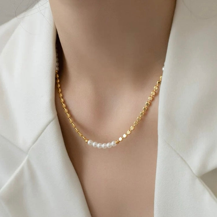 Model wearing gold aurora pearl link necklace with white blazer, elegant jewelry styling.