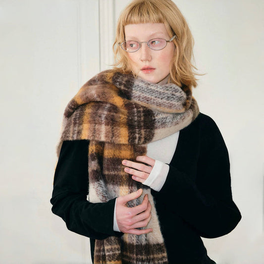Model wearing cozy Autumn Ember Plaid Scarf, a wool blend in warm brown, gold, and cream tones in yellow.
