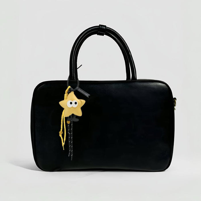 Yellow Big Eyed Stars bag charm hanging on a black bag, great for winter looks and travel days.
