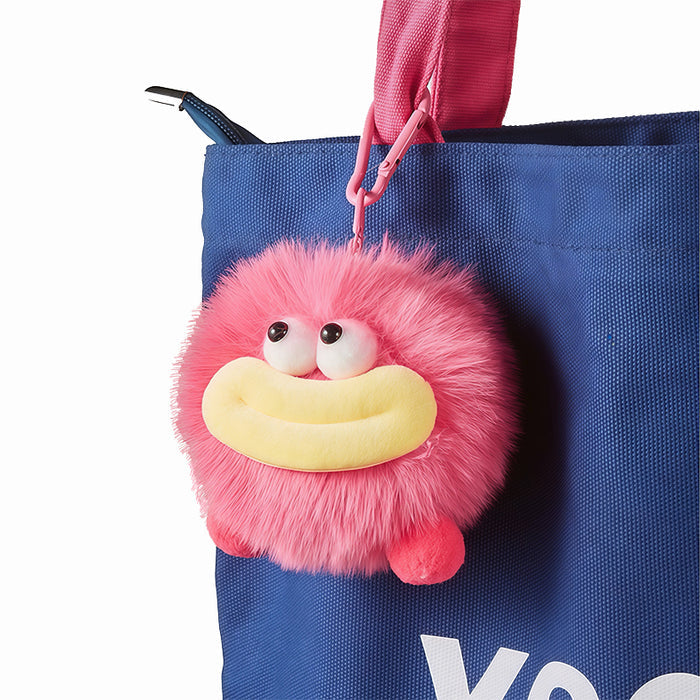 Pink coal bag charm attached to blue tote bag, playful bag personalization view.
