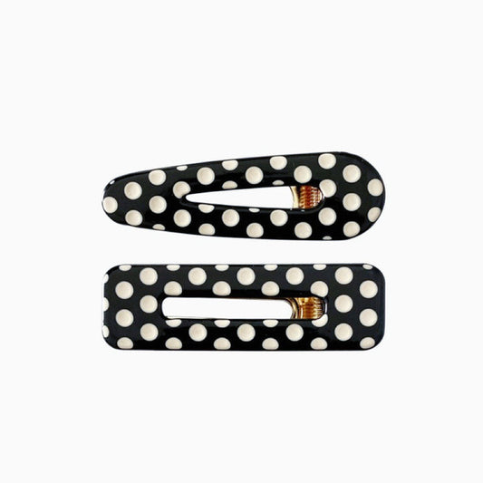 Two black acrylic hair clips with white polka dots, one is arrow shape and one is rectangular.