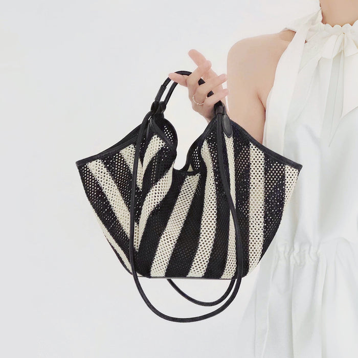 Model holding a Black and white striped polyester and PU leather basket bag handheld , great for everyday.