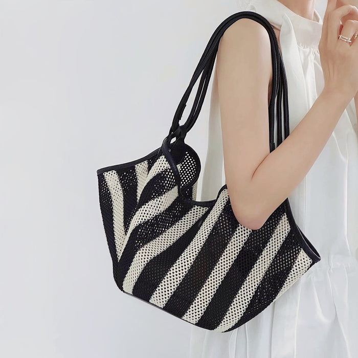 Model carrying the black and white striped basket bag on her should, wtth the adjustable strap.