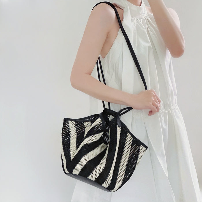 Model carrying the black and white striped basket bag on her should with the long strap style, ideal for city walks and gifting.