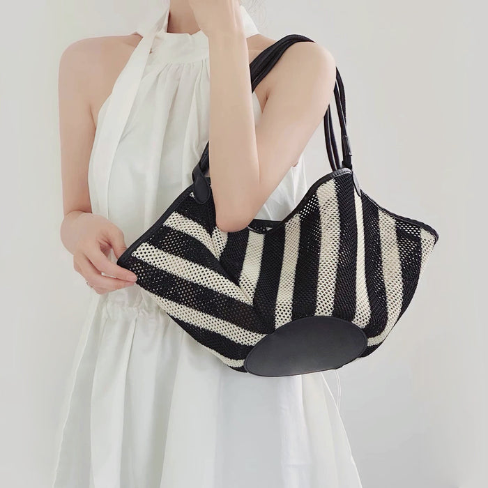 Model carrying the Black And White Striped Basket Bag on her shoulder, easy for commuting and weekends.