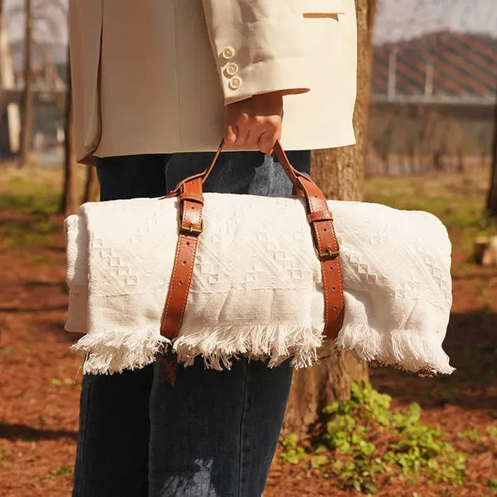 Model carrying a rolled-up blanket secured with the brown picnic strap.