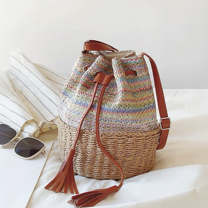 Colorful woven raffia straw bucket bag with brown PU leather drawstrings.