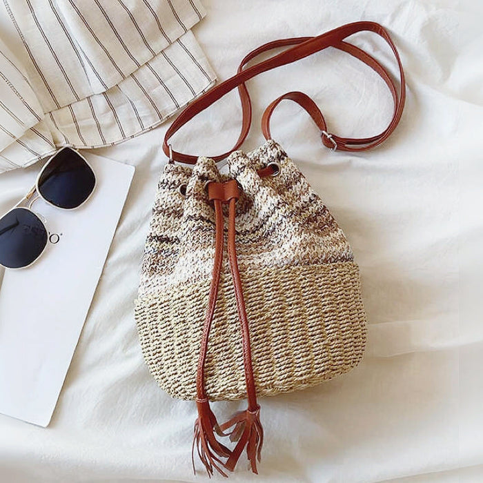 Flatlay view of the straw bucket bag with vacation accessories.