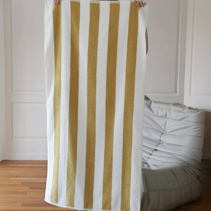 Model holding up a fully unfolded Bold Color Striped Bath Towel in white-mustard, great for bath time.