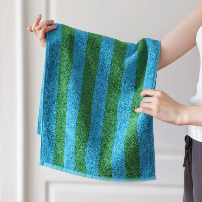 Model holding a Bold Color Striped Face Towel in blue-green, great for daily use.