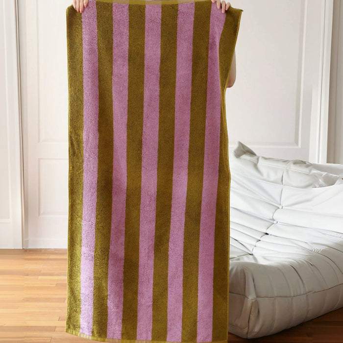 Model holding a fully unfolded Bold Color Striped Bath Towel in Rose Violet -Yellowish Brown.