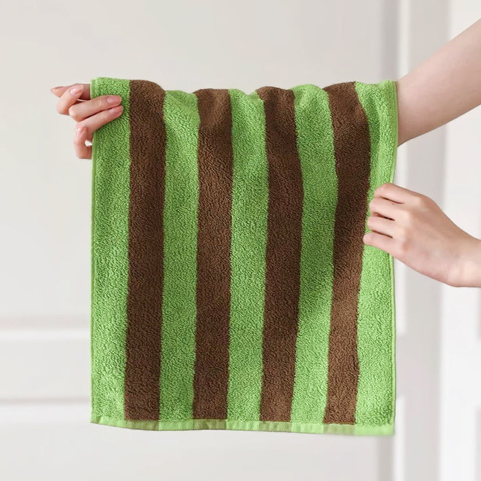 Model holding a Bold Color Striped Face Towel in Green-blue.