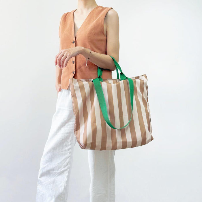 Model carrying a khaki striped  tote bag handheld, easy for commuting and weekends.