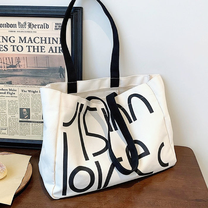 Front view of White canvas tote bag with bold black letter print.