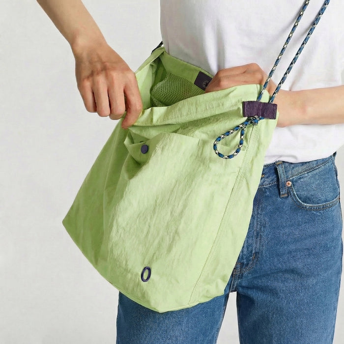 Model carrying a lime green breezy trail nylon crossbody bag, showcasing the texture detail.